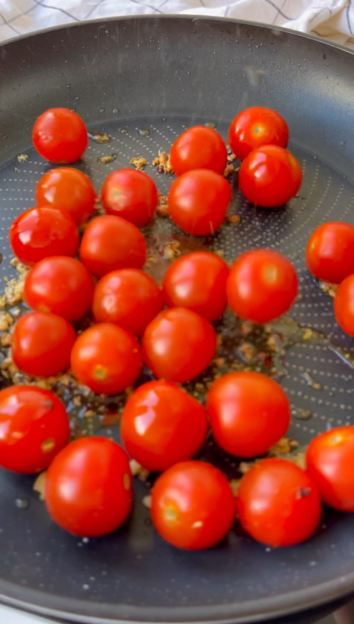 adding tomatoes to the pan to make burrata with pasta