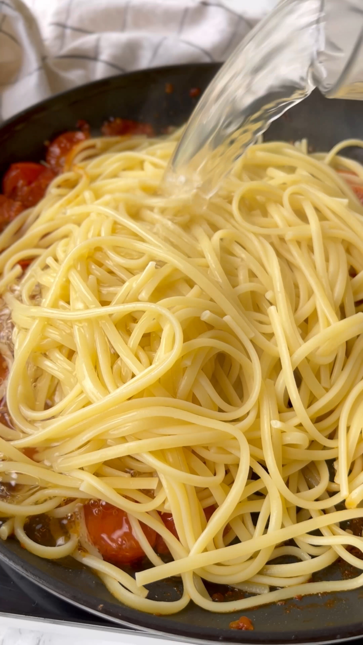 adding spaghetti to the pan to make burrata with pasta