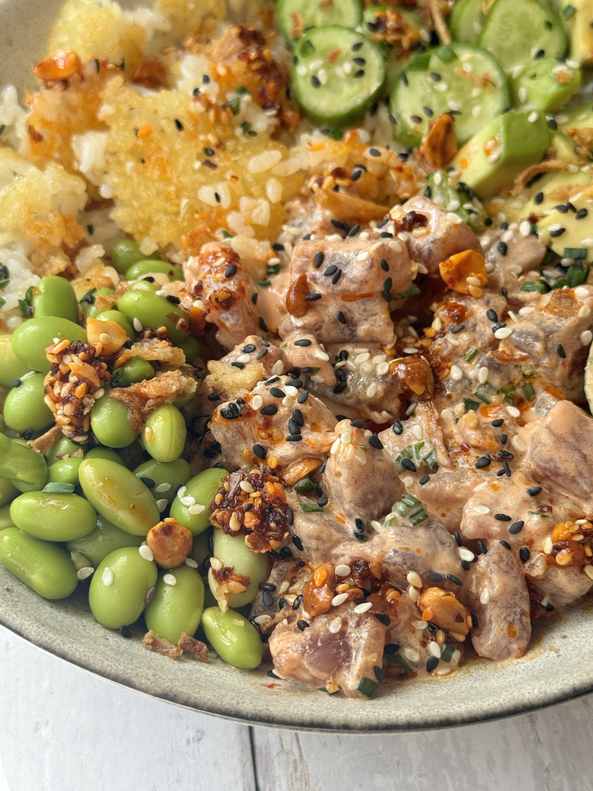 spicy tuna in a bowl with crispy rice and cucumber and avocado