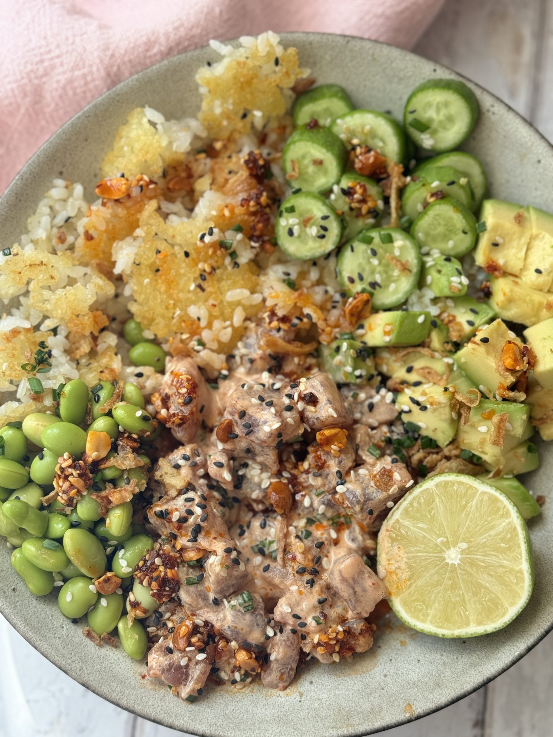 spicy tuna in a bowl with crispy rice and cucumber and avocado