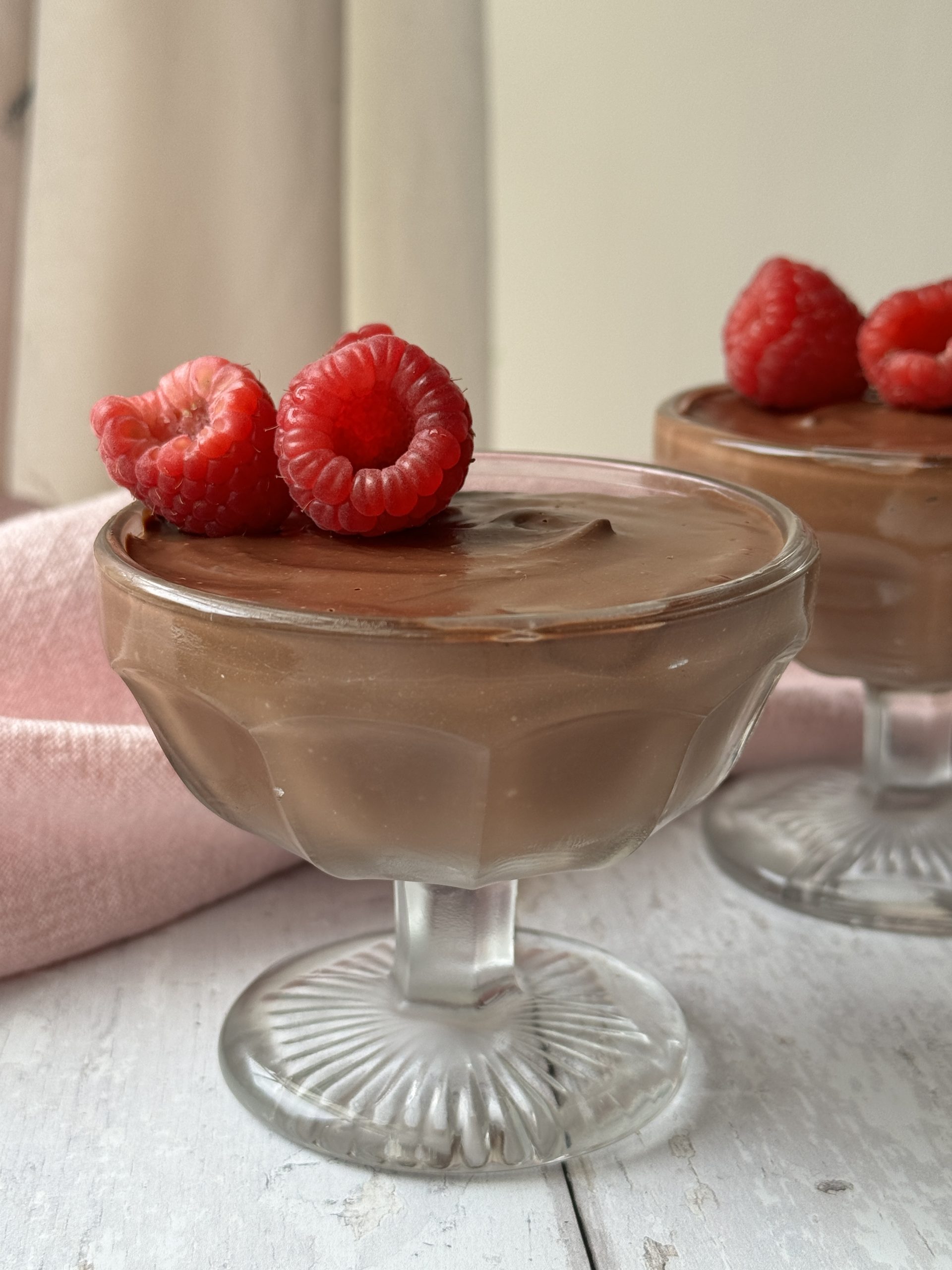 chocolate protein mousse in a glass coupe with raspberries on top