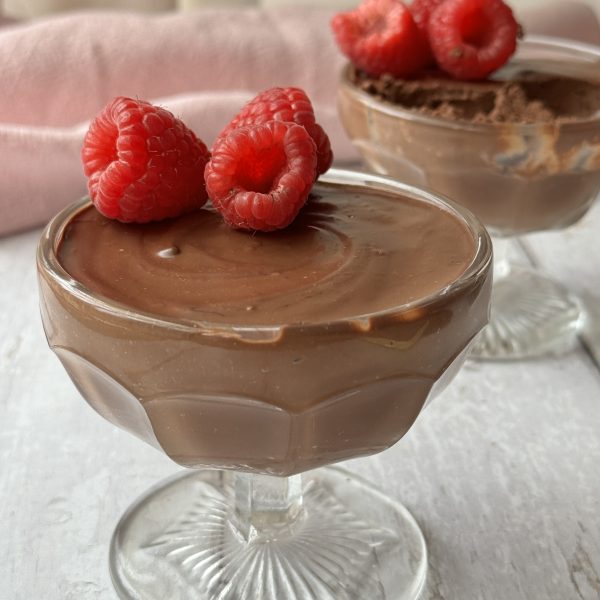 chocolate protein mousse in a glass coupe with raspberries on top