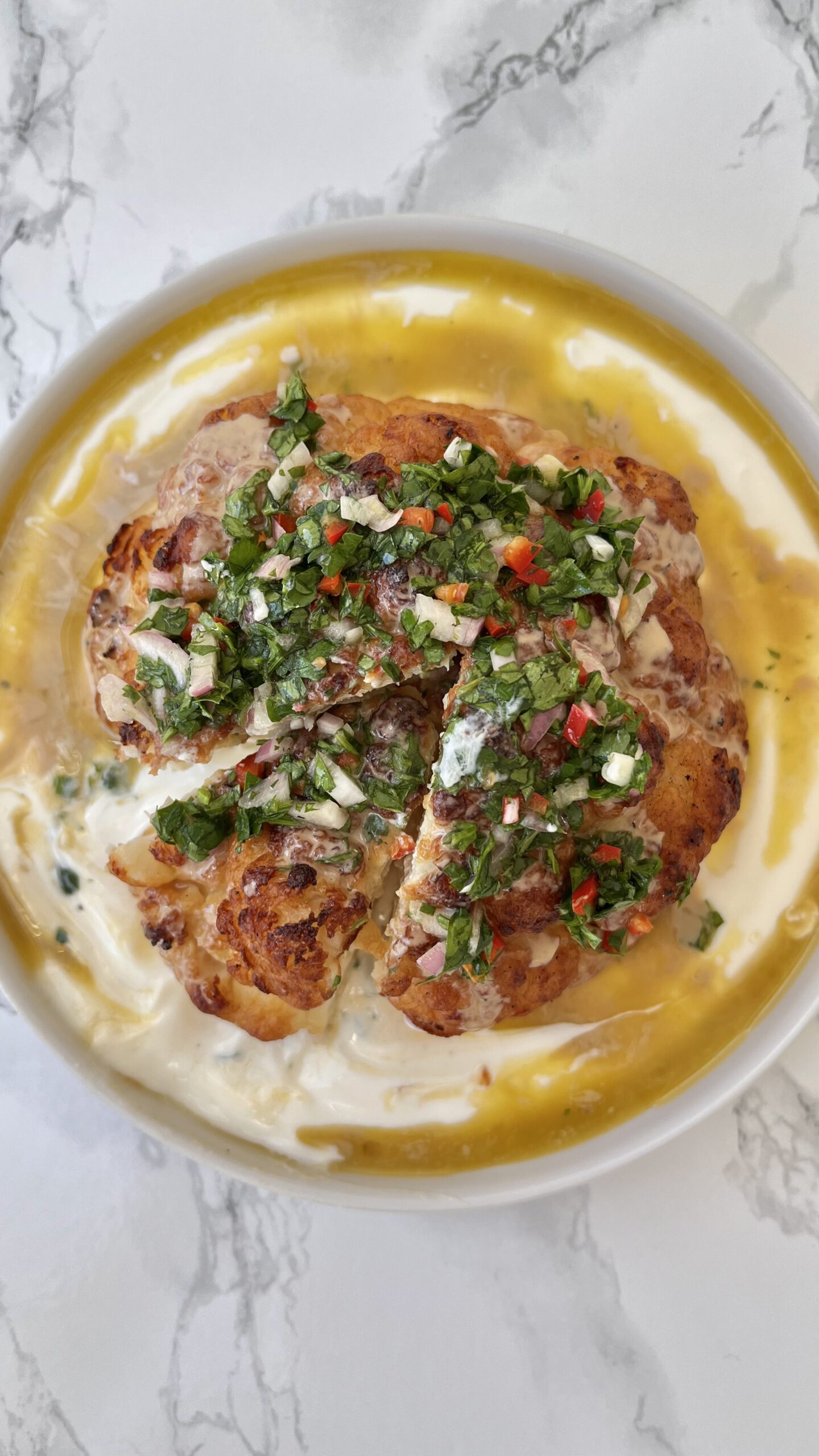 roasted cauliflower with tahini on a plate with slice removed