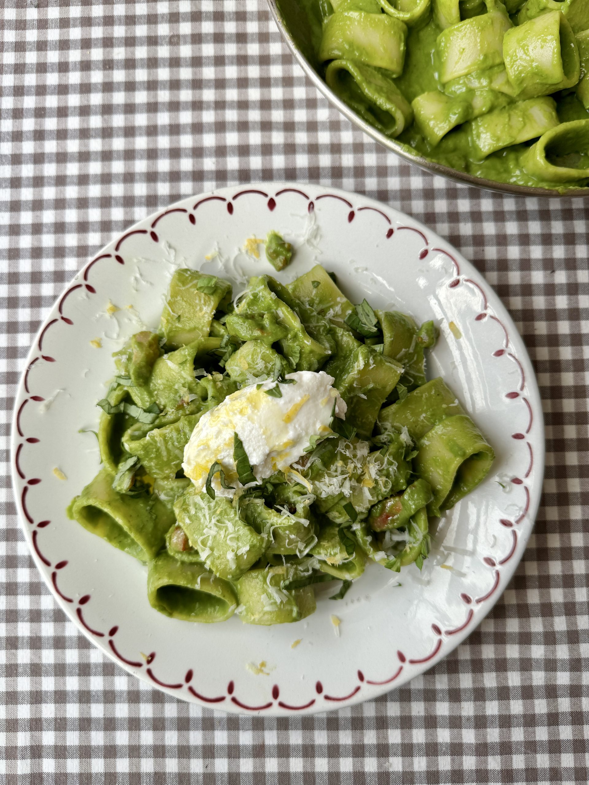 pasta in green sauce on a plate topped with cheese