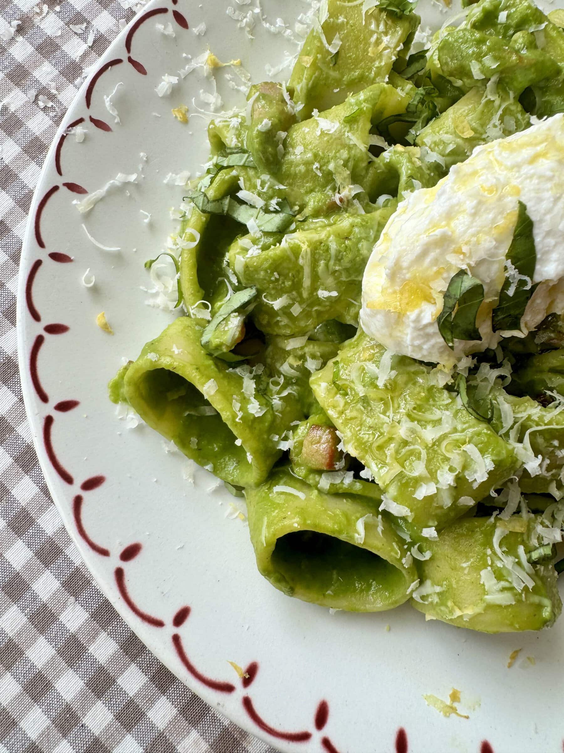 pasta in green sauce on a plate topped with cheese