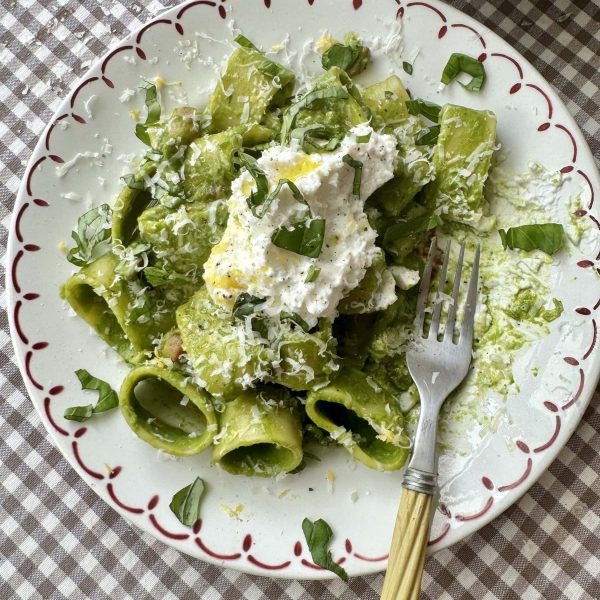 pasta in green sauce on a plate topped with cheese