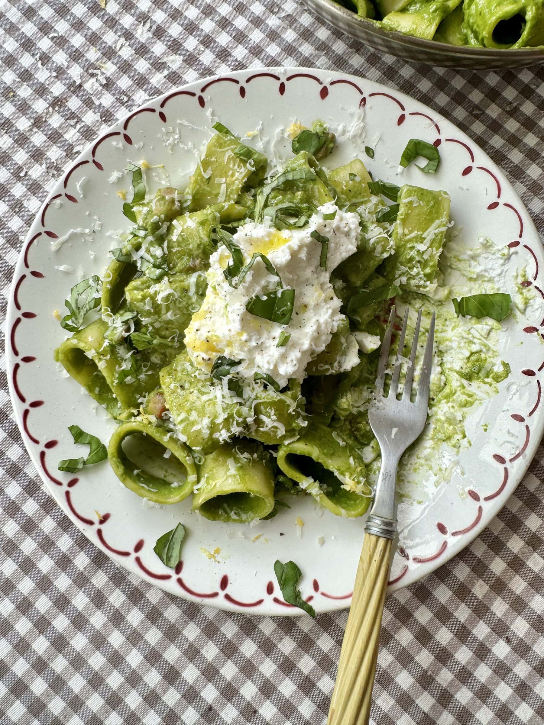 pasta in green sauce on a plate topped with cheese