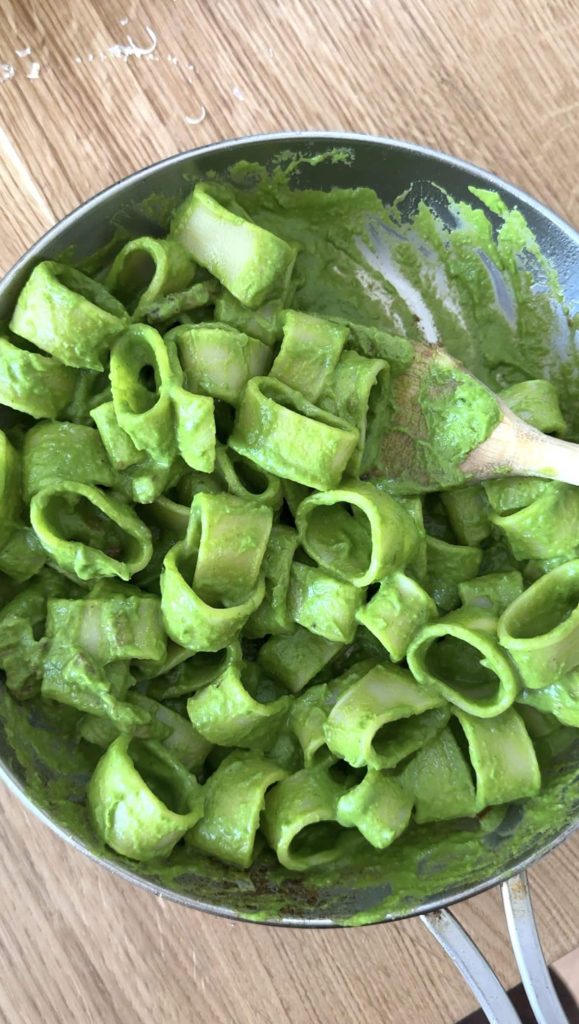 pasta in green sauce in a silver frying pan