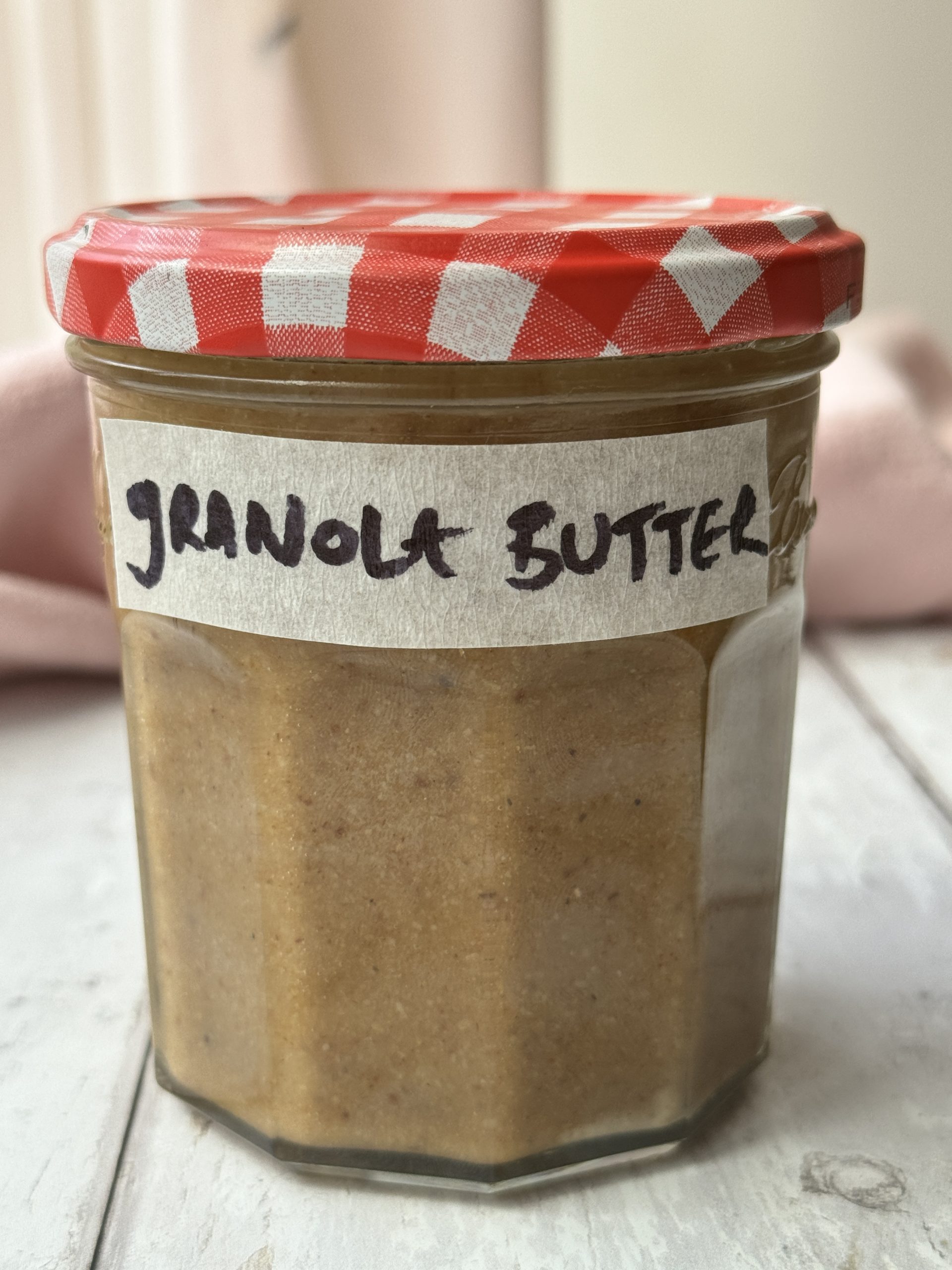 a jar of granola butter with a gingham lid and a label that reads granola butter