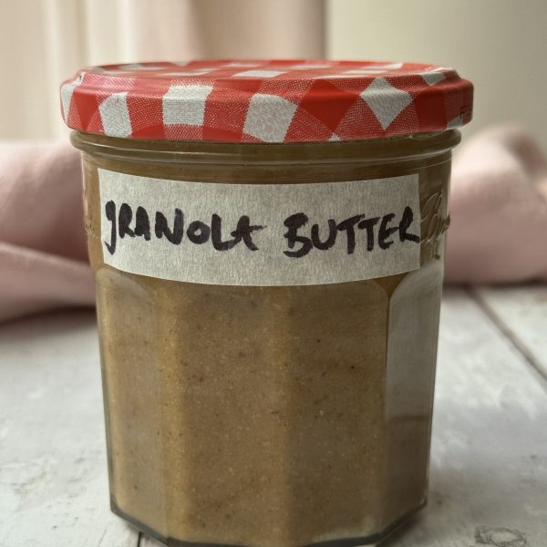 a jar of granola butter with a gingham lid and a label that reads granola butter