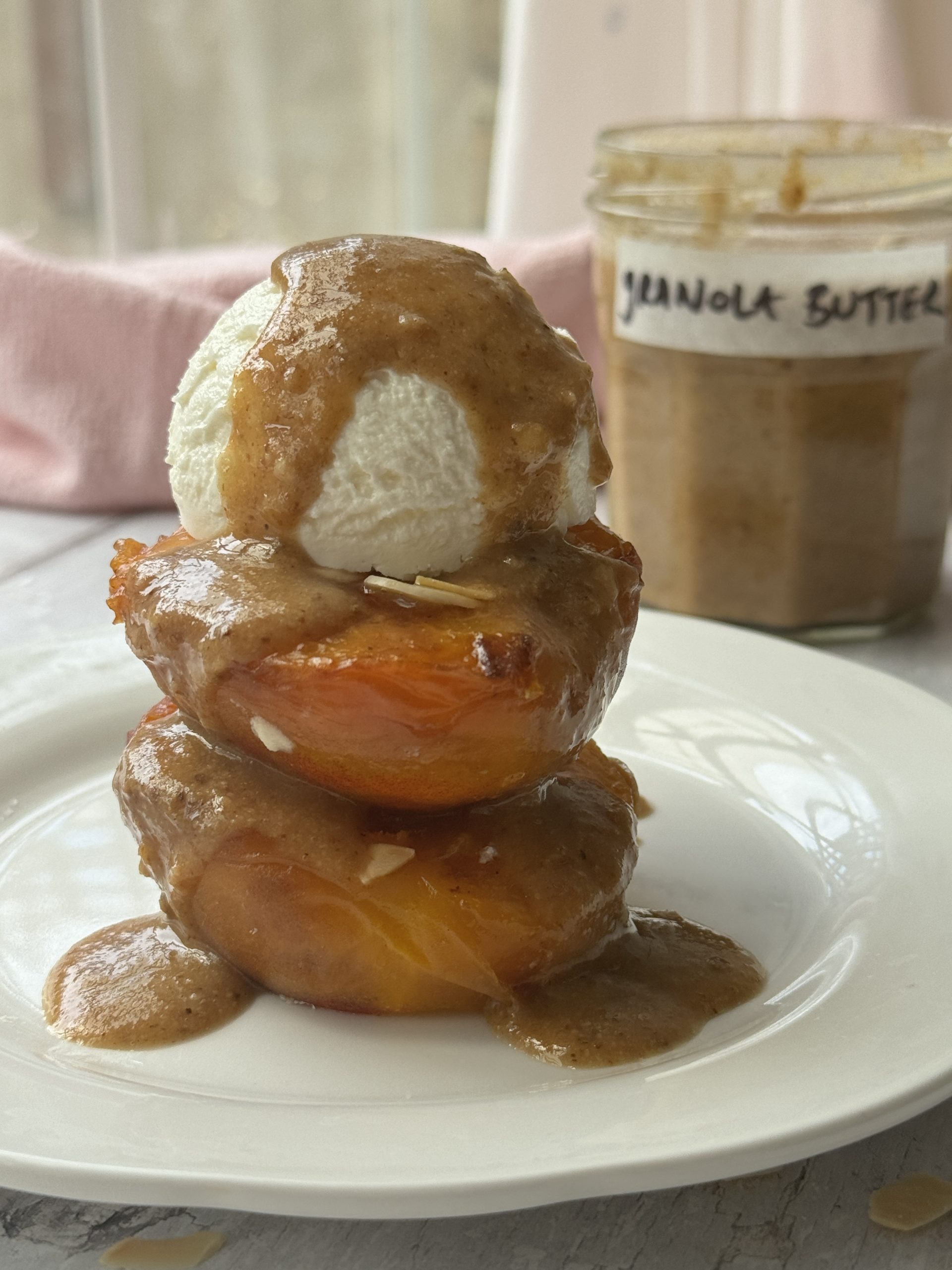 granola butter on roasted peaches on a white plate