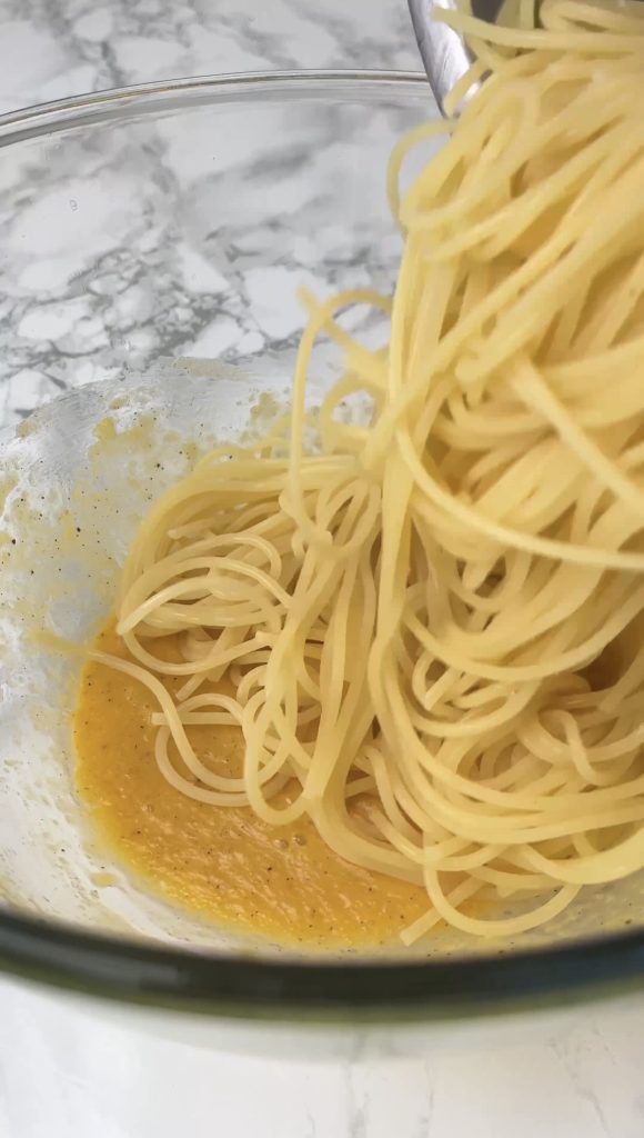 adding spaghetti to carbonara with guanciale