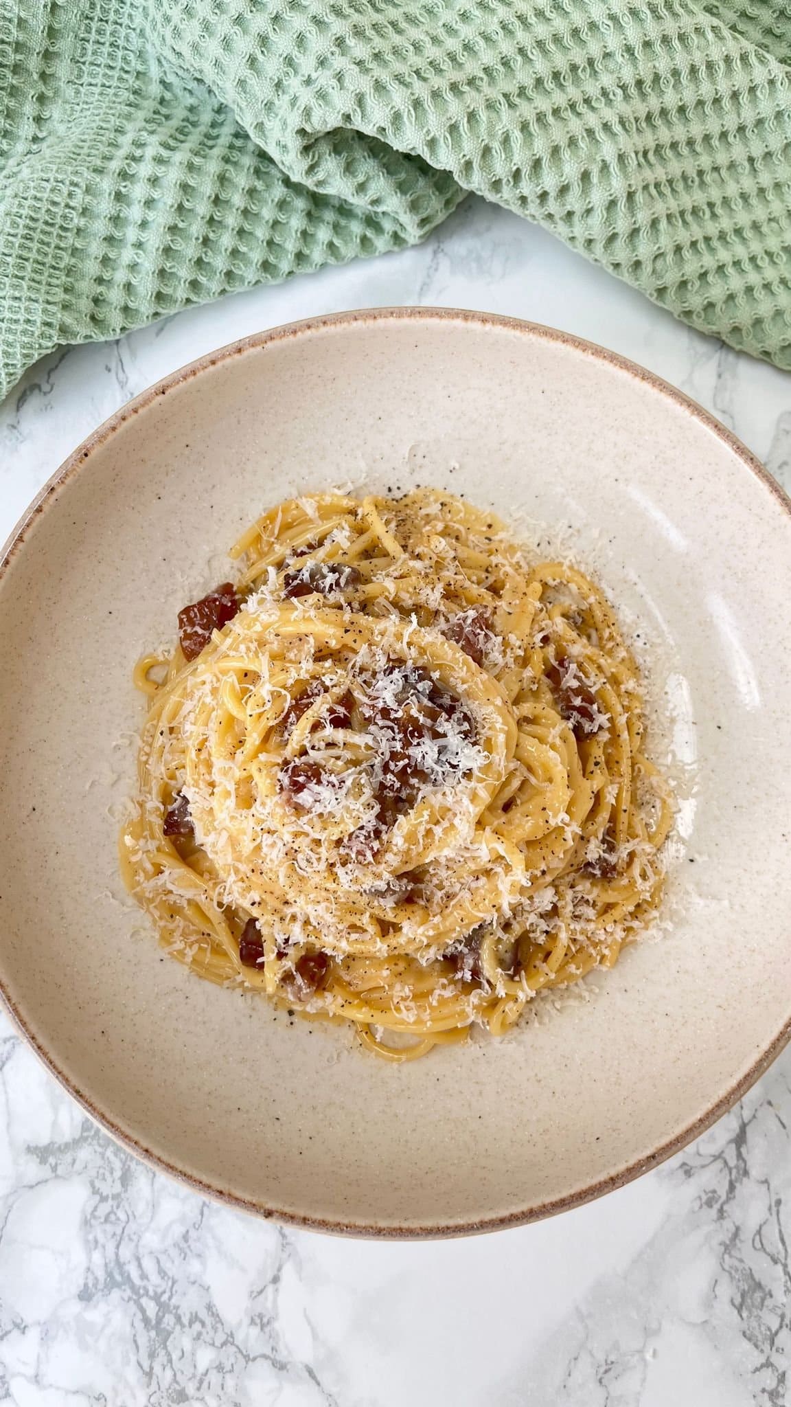 carbonara with guanciale in a beige bowl