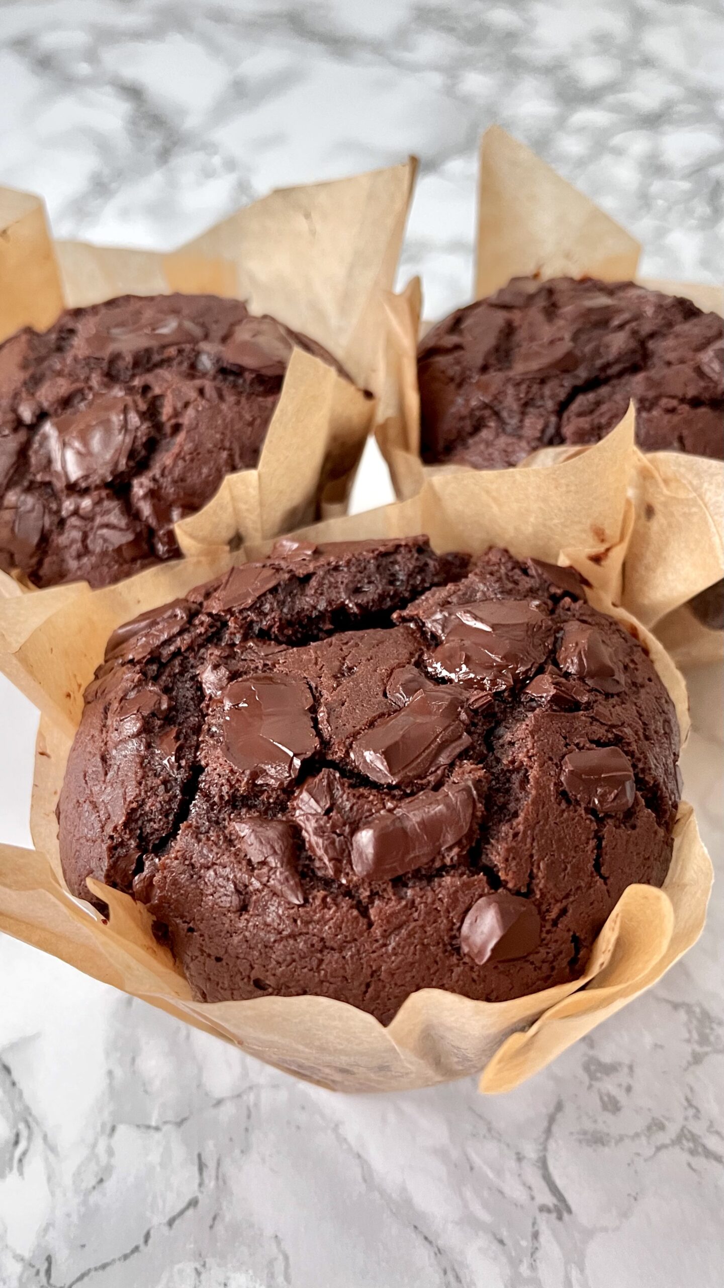 image of 3 chocolate chunk muffins in greaseproof liners.