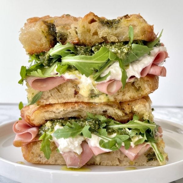 mortadella burrata sandwich with rocket, pesto, stacked on a plate