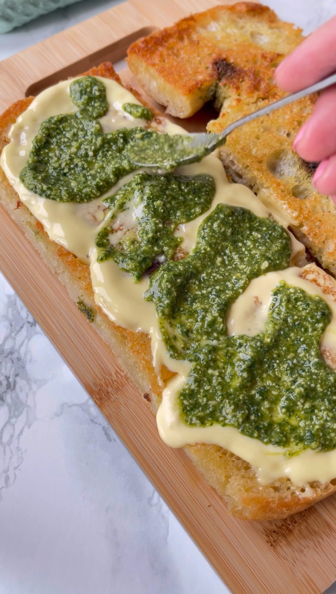 adding pesto to mortadella burrata sandwich