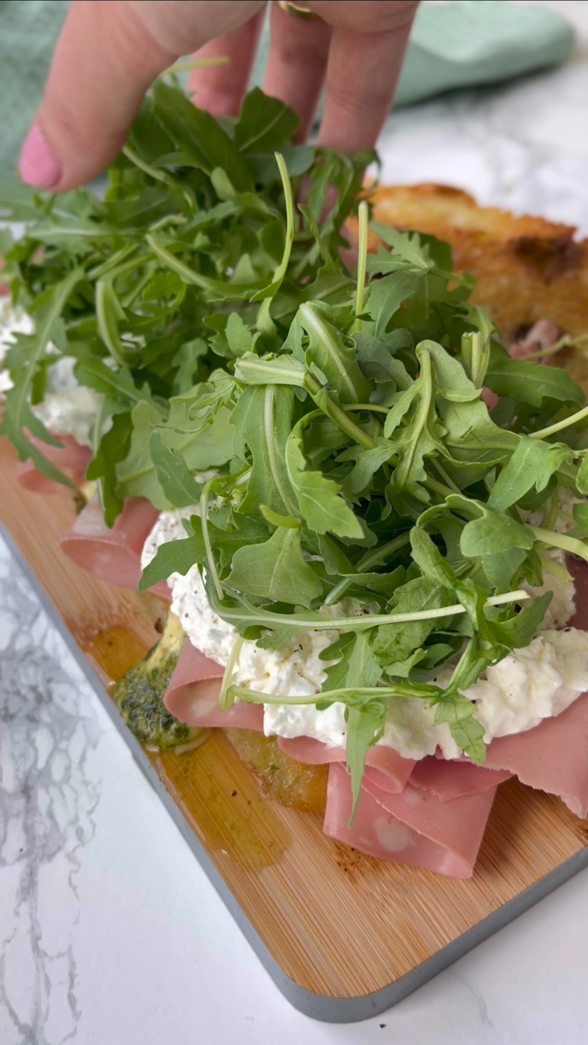 adding rocket to mortadella burrata sandwich