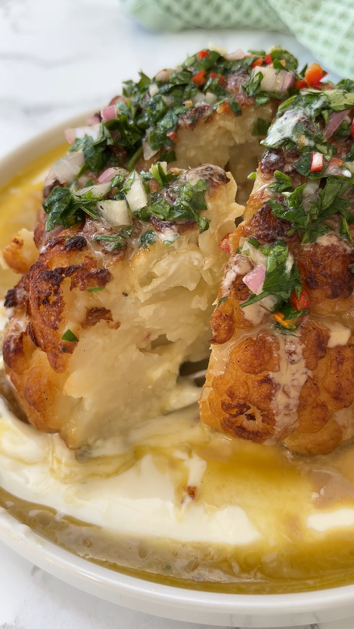 roasted cauliflower with tahini on a plate with slice removed