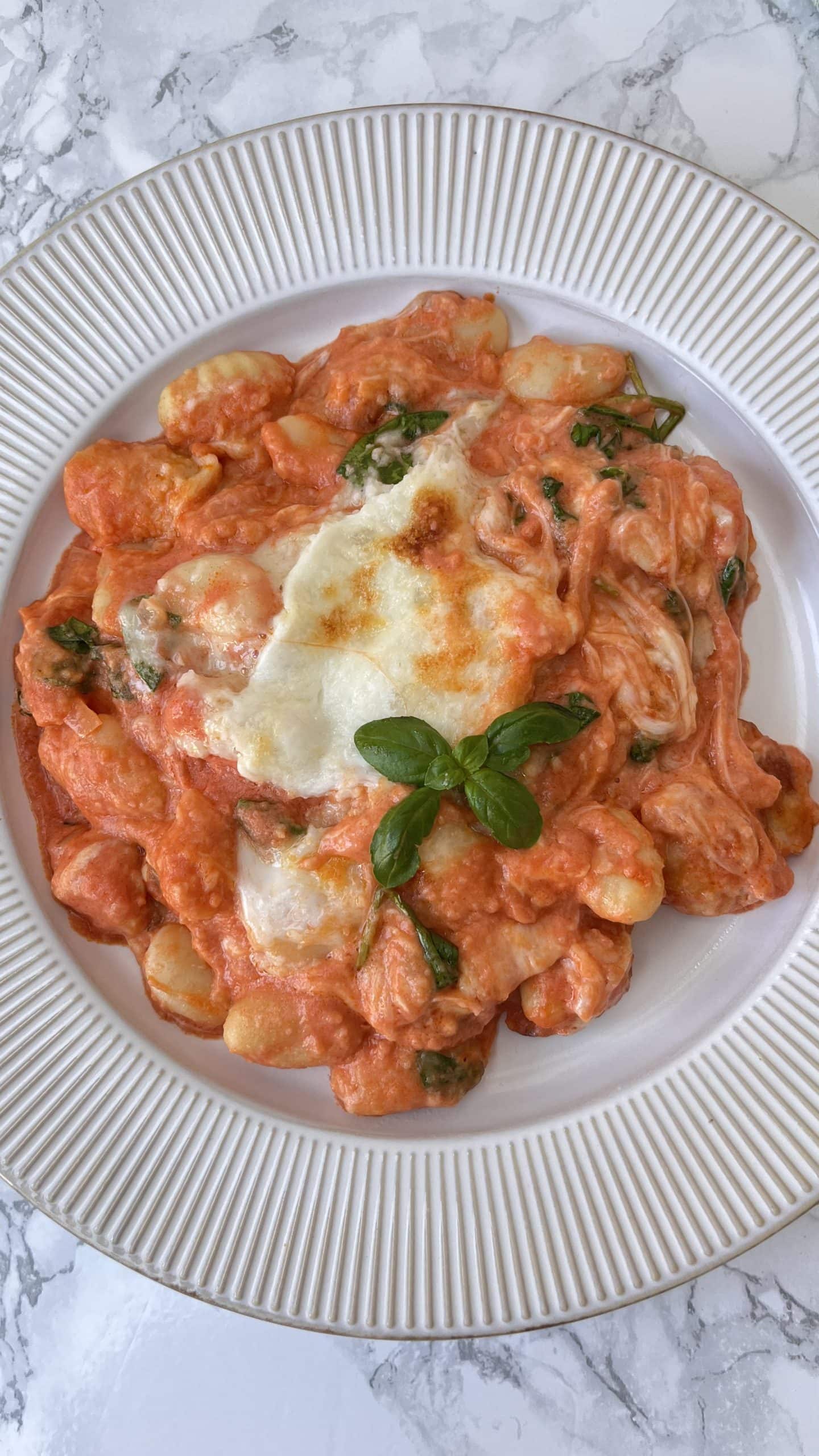 Cheesy Tomato Baked Gnocchi on a plate with fresh basil on top