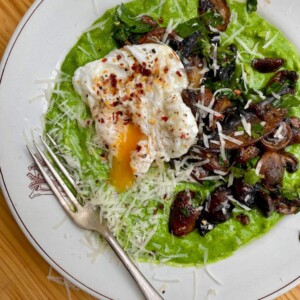 super green orzo on a white bowl with garlic mushrooms and poached egg on top.