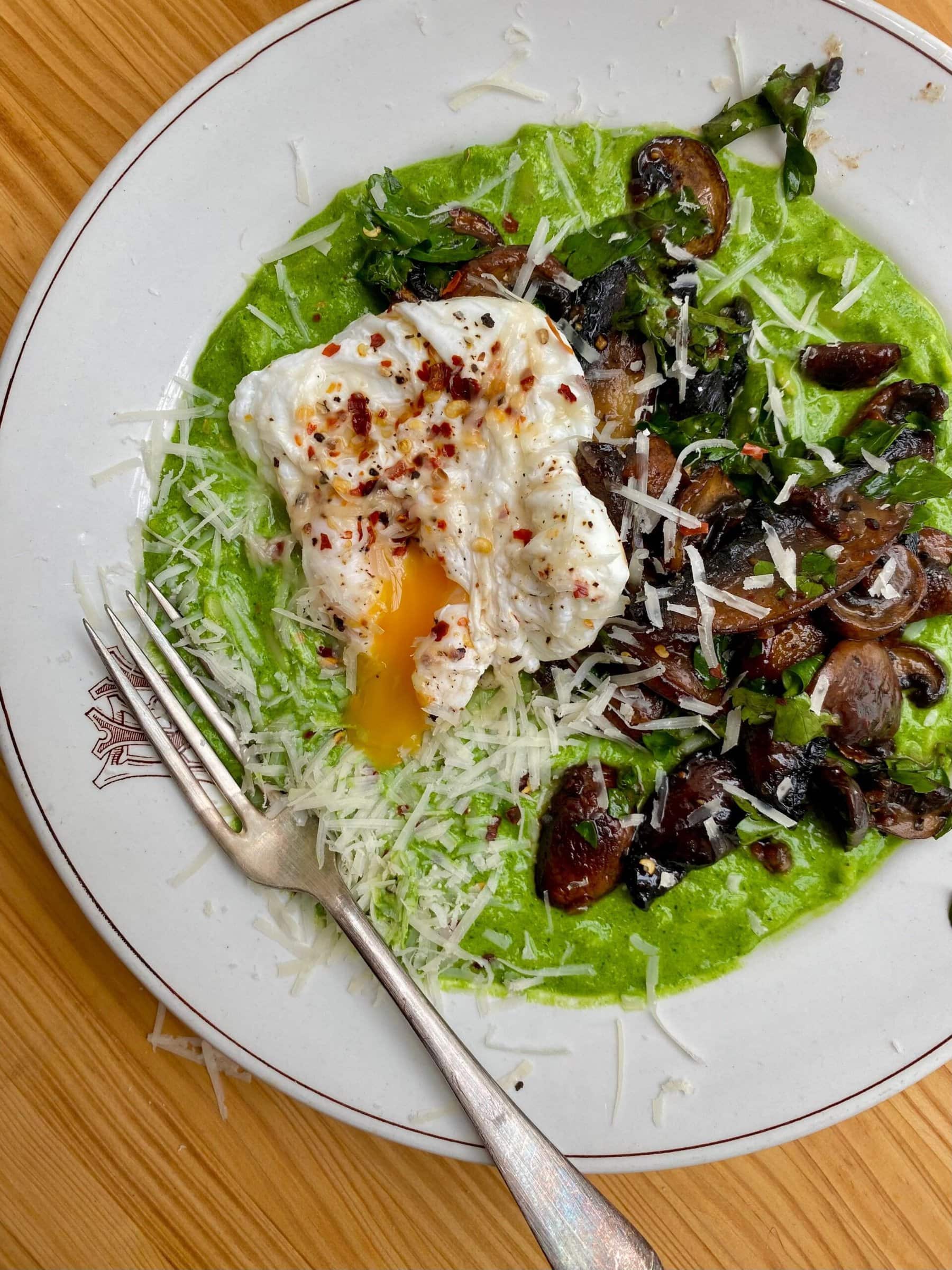 super green orzo on a white bowl with garlic mushrooms and poached egg on top.