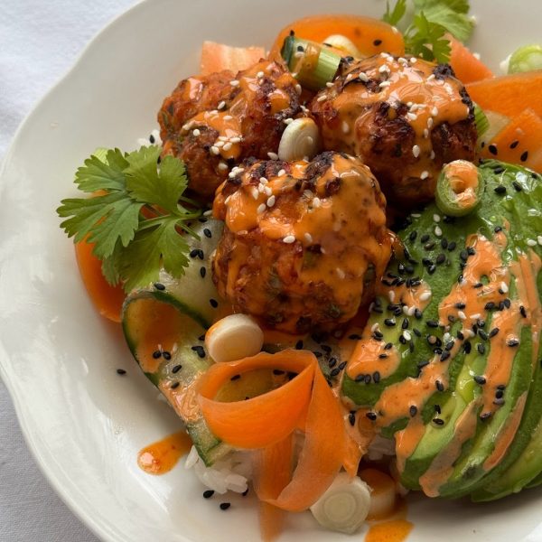 Close up of Korean flavoured salmon fishcakes served over rice with sliced avocado and a gochujang mayo drizzle.