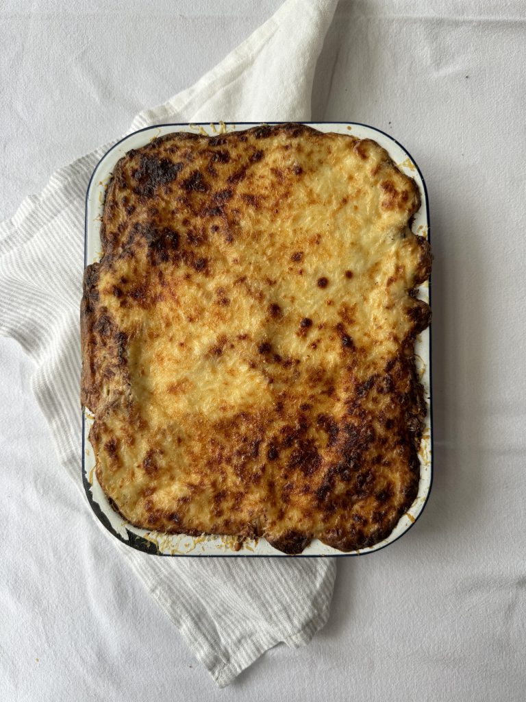A rectangular dish of lasagne, baked with crispy golden brown cheese on top