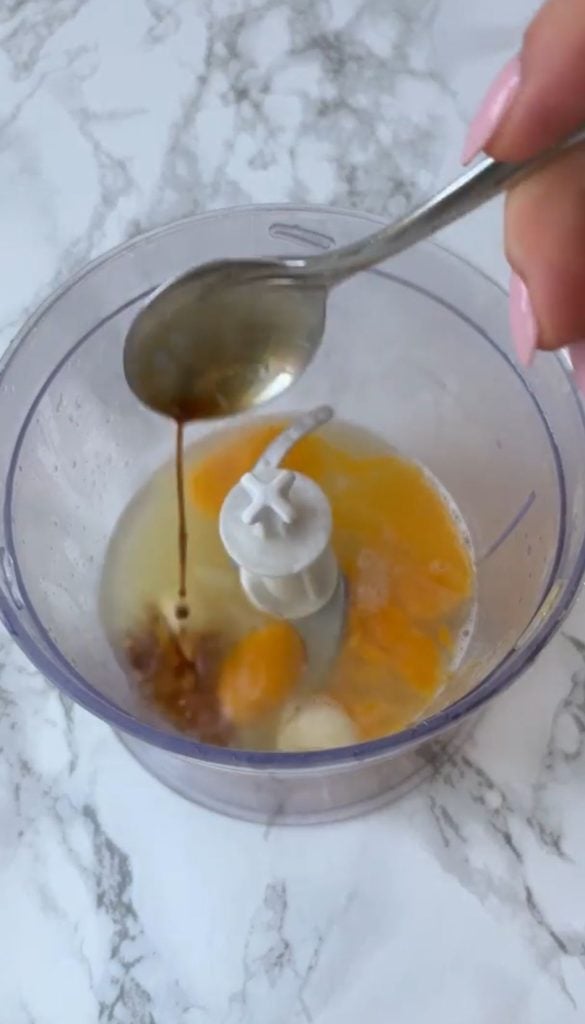 Adding worcestershire sauce to a blender with egg yolks, lemon, garlic