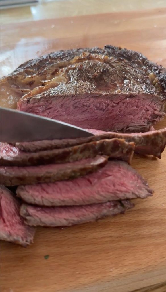 Knife slicing medium rare rib eye steak