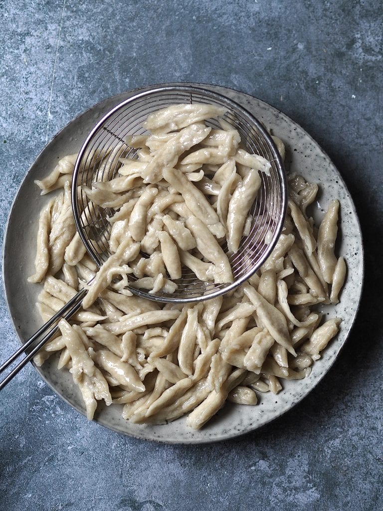 Boiled scissor-cut noodles on a grey plate.