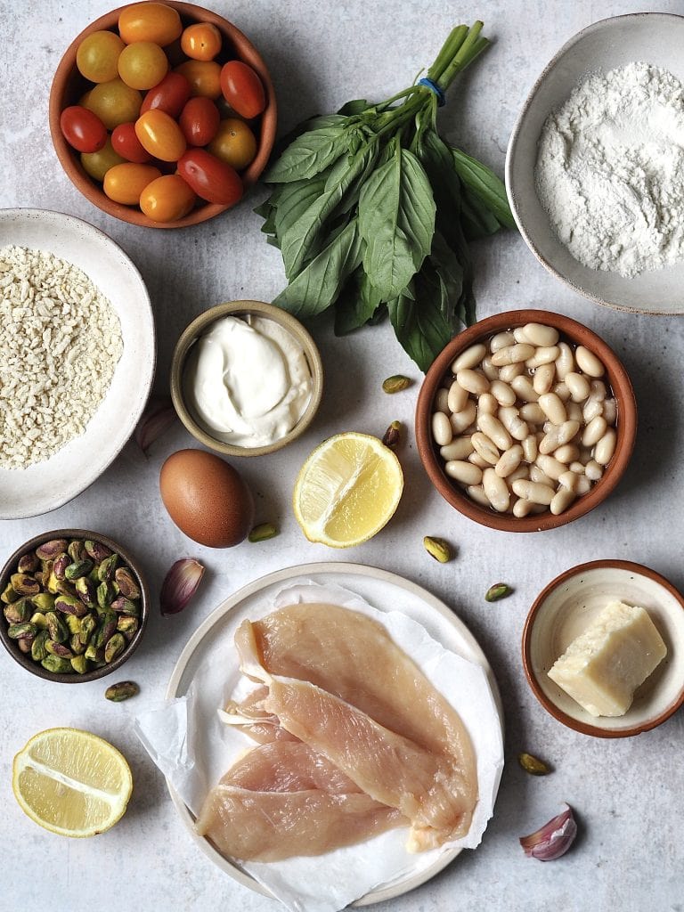 Ingredients for Crispy Baked Chicken with Tomatoes, Basil and Cannellini Beans on a grey background.