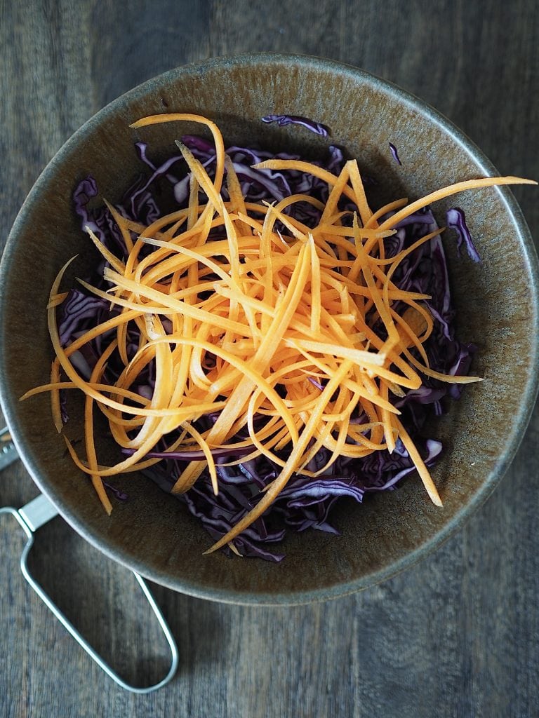 Shredded carrot and red cabbage in a bowl for making slaw.