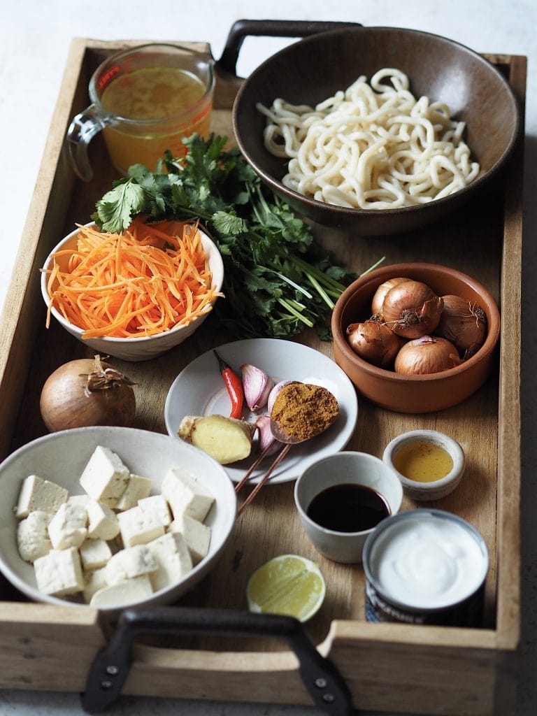 Ingredients to make a udon soup on a wooden tray.