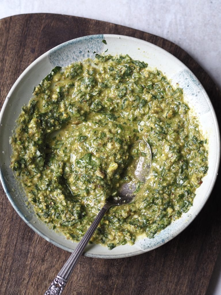 Close up of a grey bowl of homemade basil pesto.