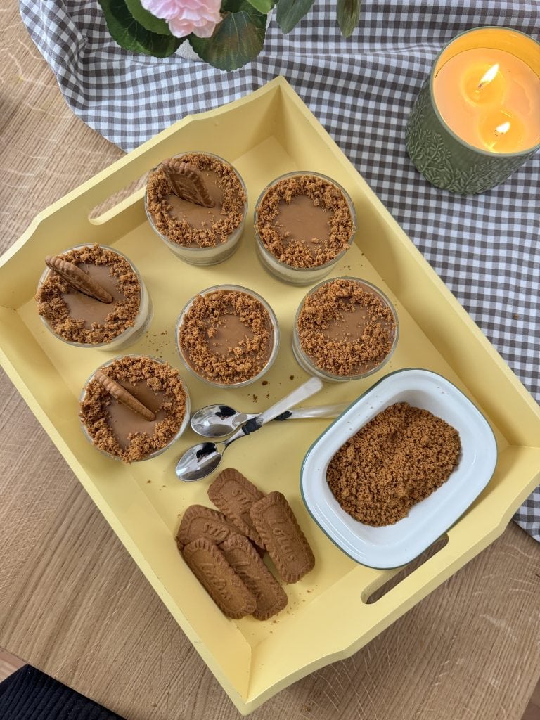 No bake biscoff cheesecakes on a wooden tray with extra Biscoff biscuits