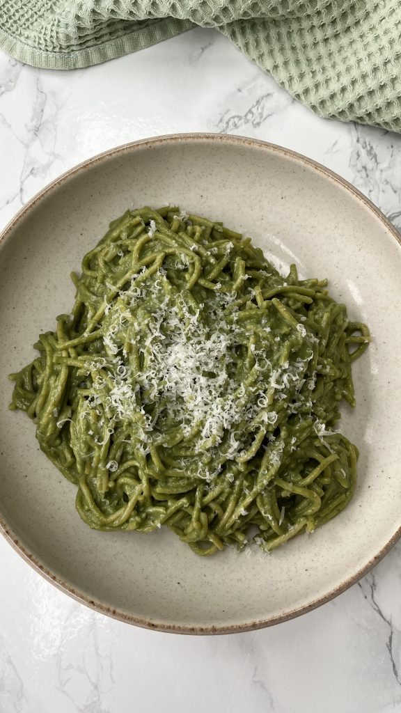 A bowl of green Ricotta Pesto Pasta in a beige bowl