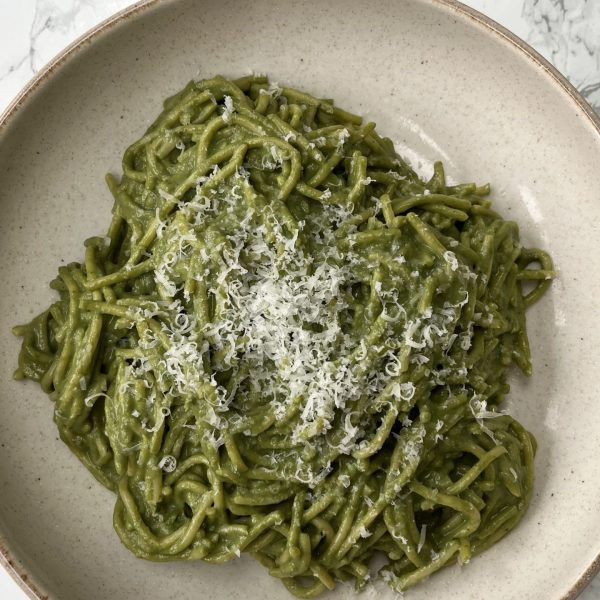 A bowl of green Ricotta Pesto Pasta in a beige bowl