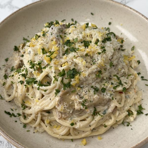 Boursin Pasta with Artichokes in a beige bowl, topped with parsley and lemon zest