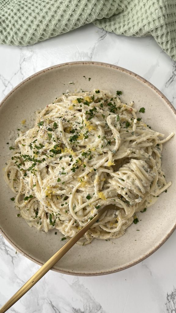 Boursin Pasta with Artichokes in a beige bowl with a fork in it