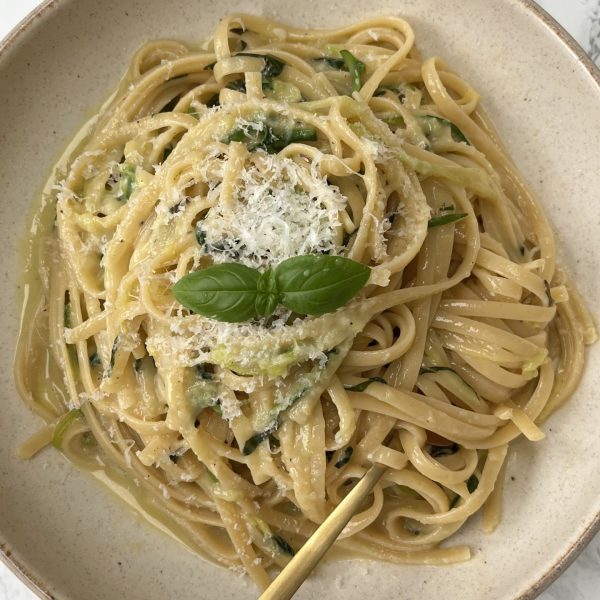 Lemon Courgette Pasta in a beige bowl with a fork in the pasta