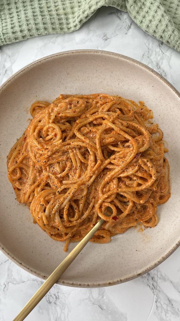 Spicy Nduja Pasta in a beige bowl with a fork twirled into the spaghetti