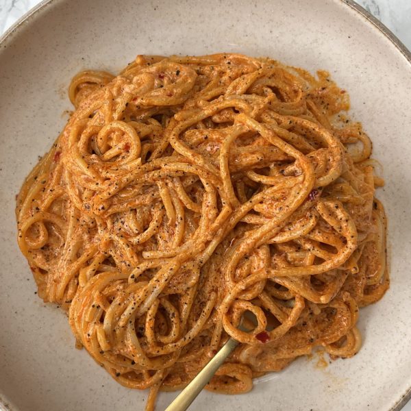 Spicy Nduja Pasta in a beige bowl with a fork twirled into the spaghetti