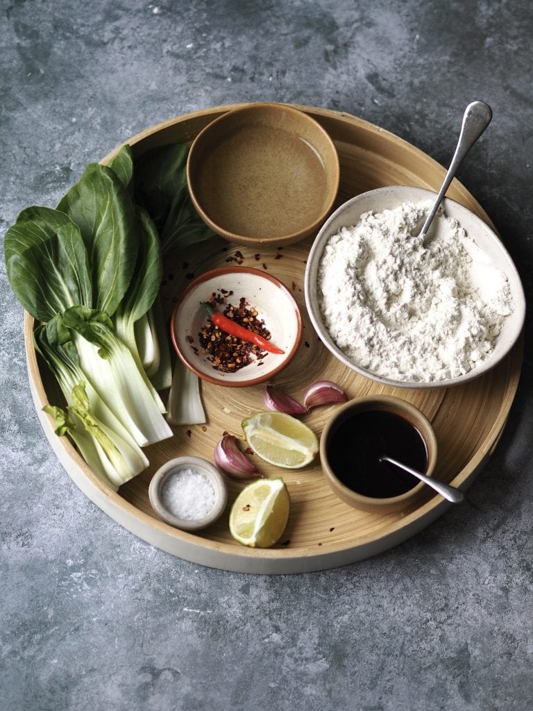 Ingredients to make scissor-cut noodles in homemade chilli and garlic oil on a round tray.