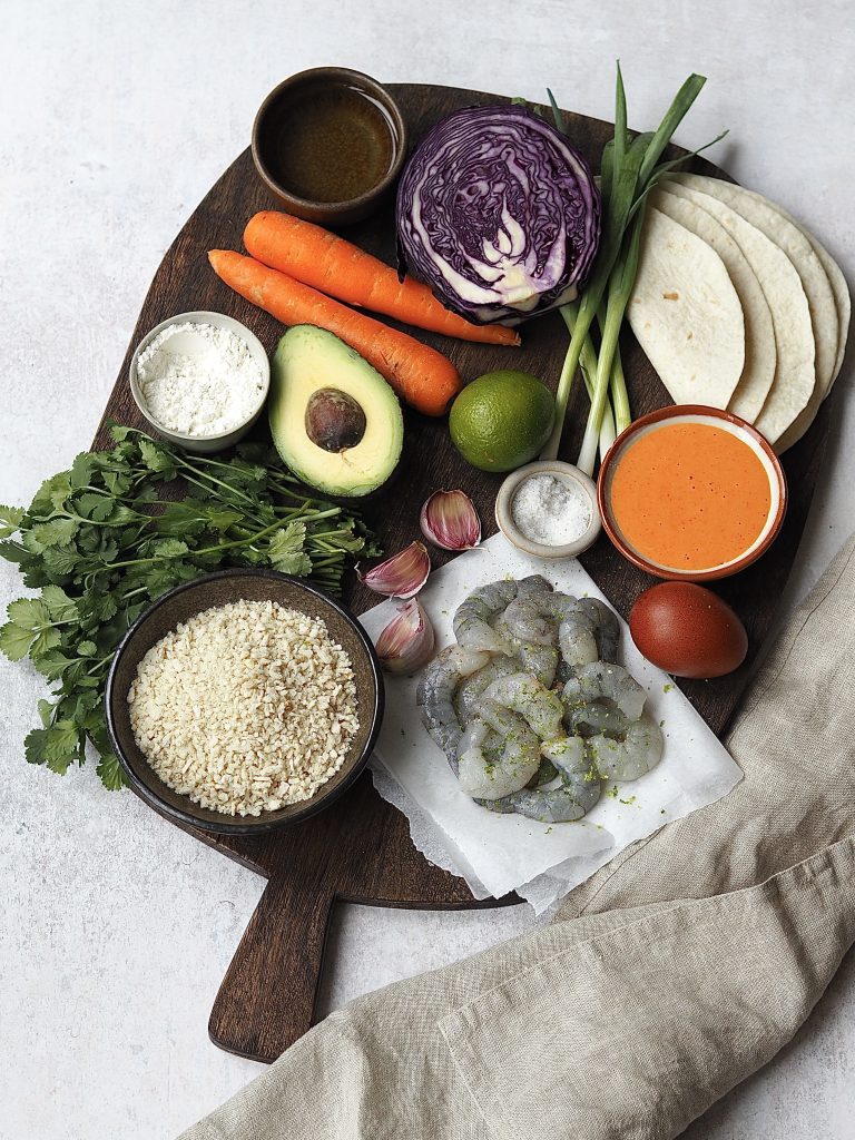 Ingredients to make panko Prawn tacos on a wooden board.