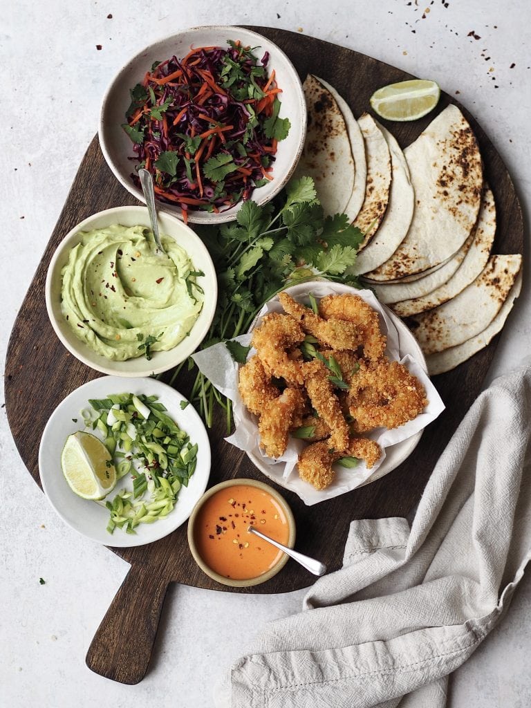 All the fixings for panko prawn tacos on a serving board.