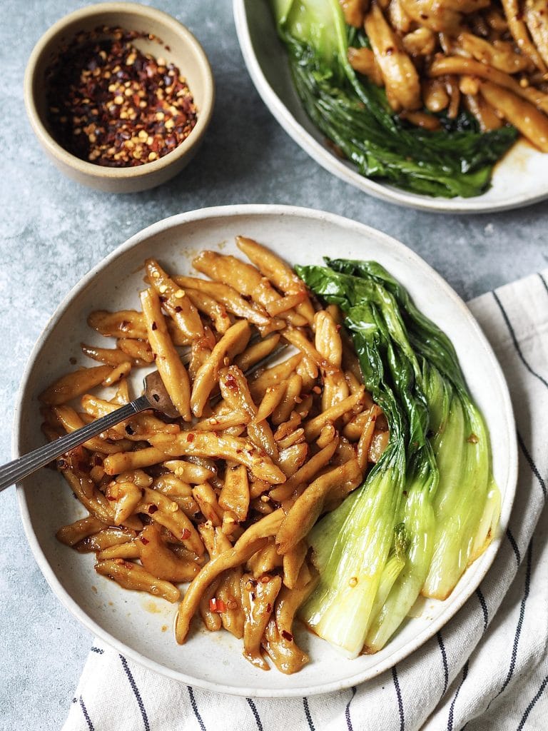 Plate of scissor cut noodles in chilli and garlic oil with pak choi stir fried on the side.