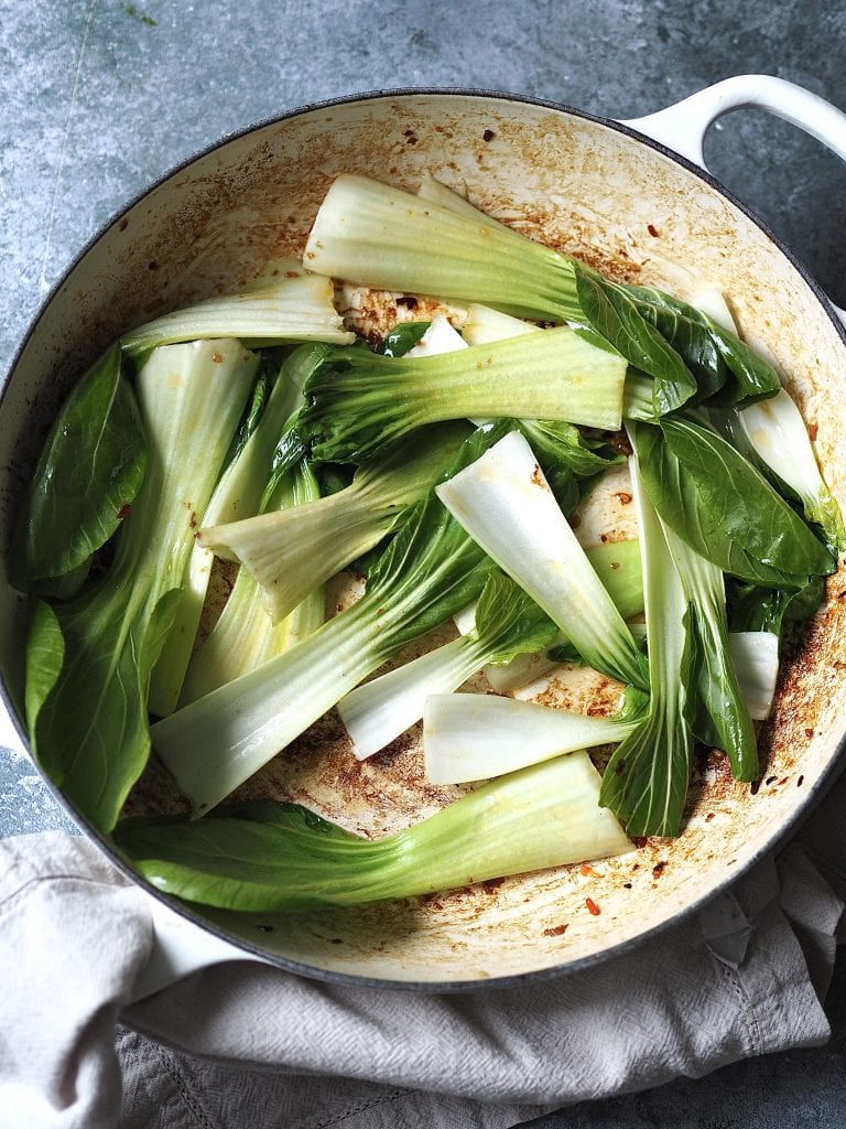 A casserole dish with raw pak choi leaves ready to be stir fried.