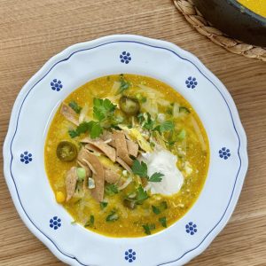 Bowl of chicken chilli con carne in a white bowl with blue flowers, topped