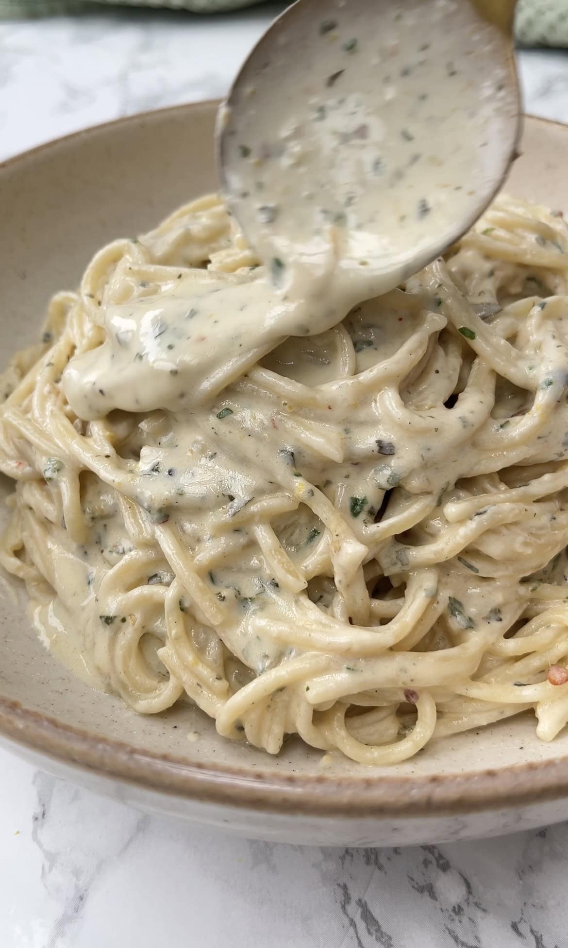 spooning sauce over baked boursin pasta.