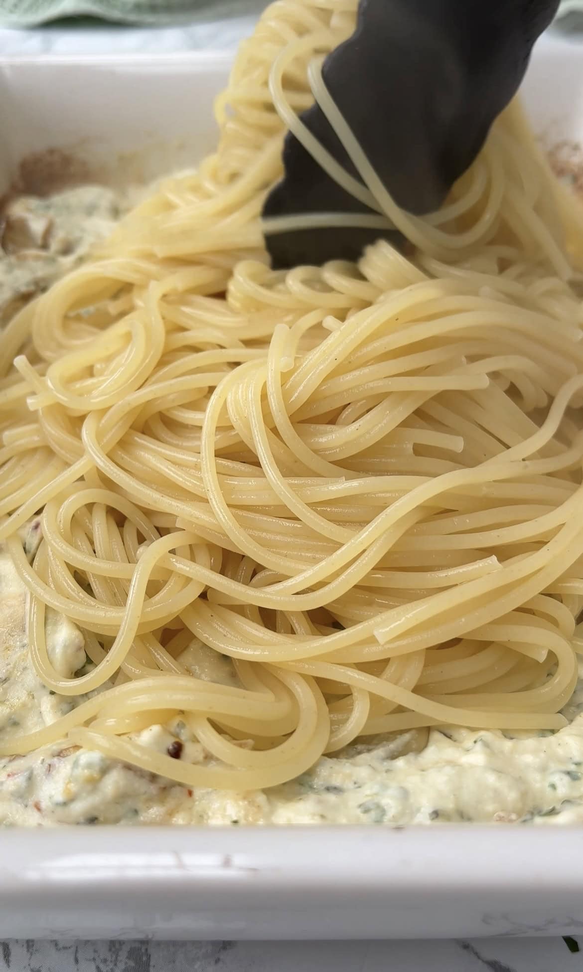 adding the cooked spaghetti to baked boursin.